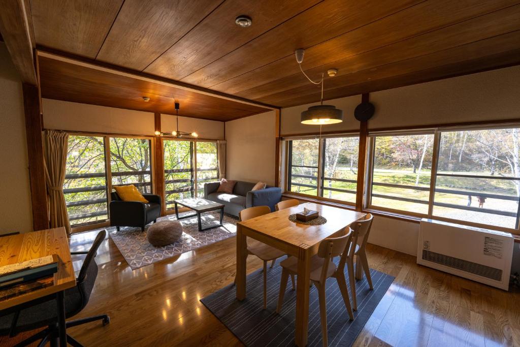ein Wohnzimmer mit einem Tisch, Stühlen und Fenstern in der Unterkunft NORTHSTAR Loft in Matsumoto