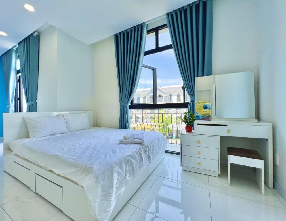 a bedroom with a bed and a desk and a window at Ngân Hà GrandWorld Phú Quốc in Phu Quoc