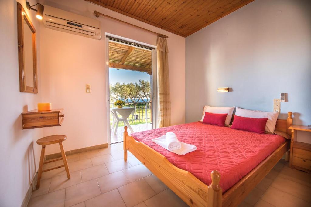 Un dormitorio con una cama con sábanas rojas y una ventana en Jimmy's Sea View Studios, en Tragaki