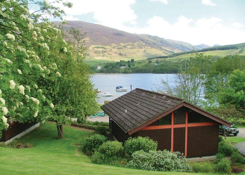 a small cabin with a lake in the background at Lochearnhead Loch Side in Lochearnhead