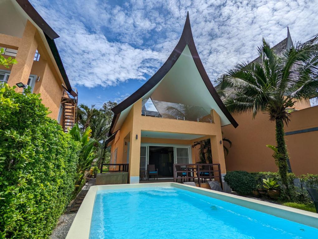 a villa with a swimming pool in front of a house at Blue Sky Pool Villa in Trat
