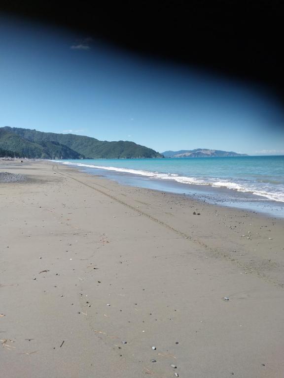 an empty beach with footprints in the sand at Rarangi Seaview On the Beach B&B in Blenheim