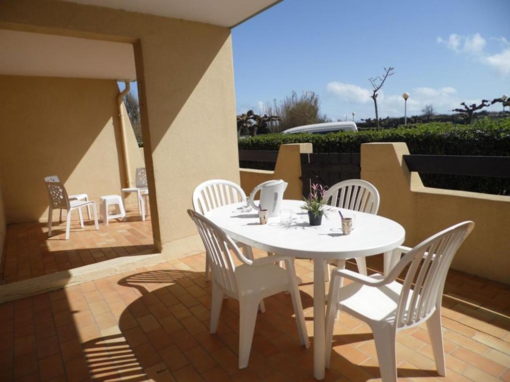 una mesa blanca y sillas en un patio en Appartement Marseillan-Plage, 2 pièces, 4 personnes - FR-1-326-599, en Marseillan