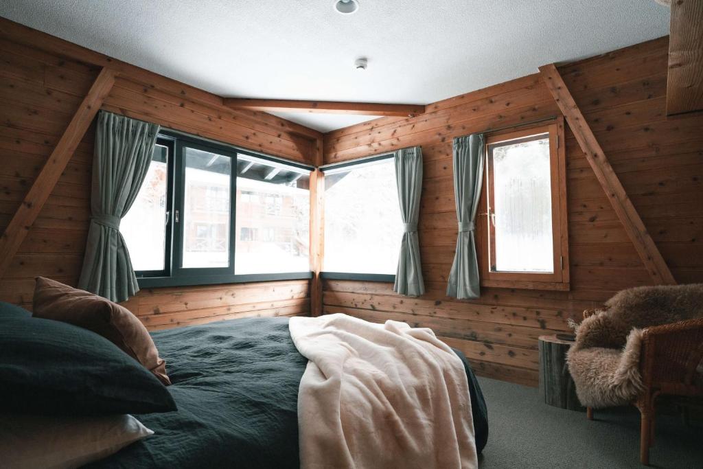 a bedroom with a bed in a room with wooden walls at Sugi Chalet in Myoko