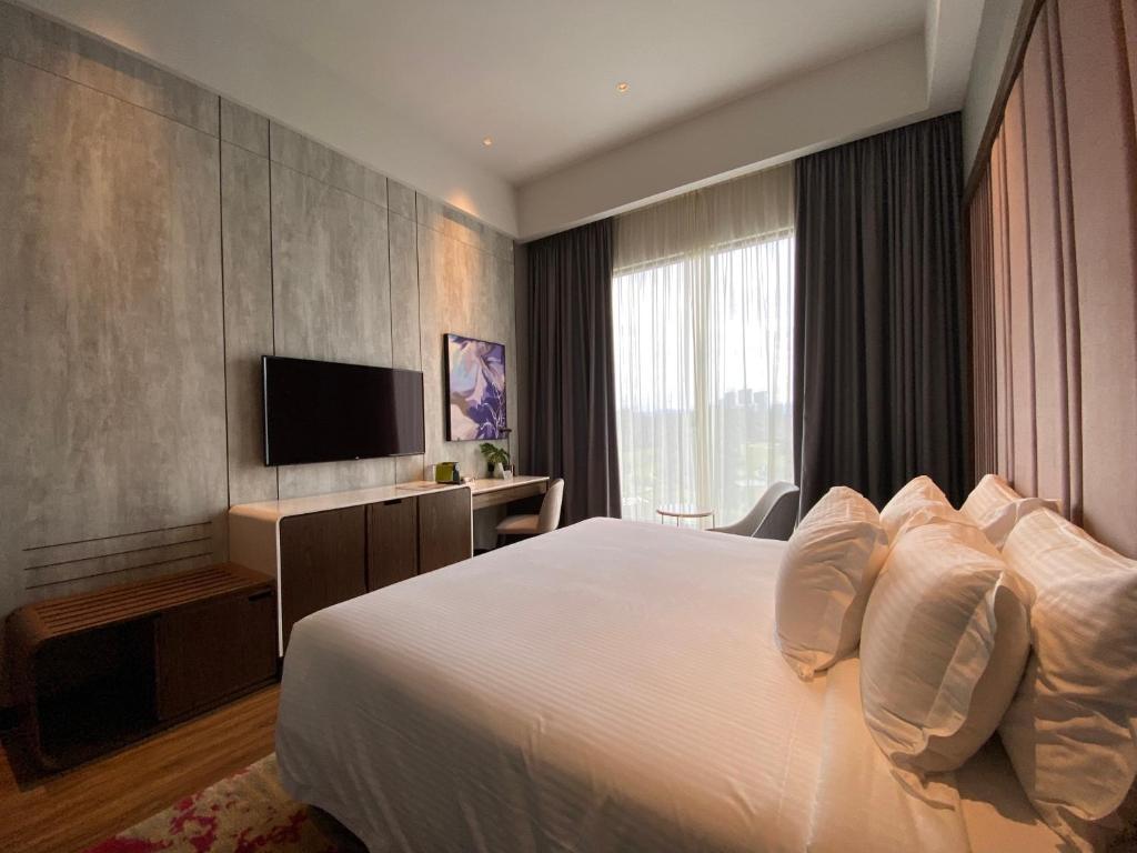 A king room photographed from beside the bed, with a television wall and bright window.