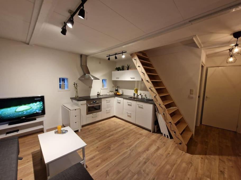 een grote keuken met een trap in een kamer bij Huisje in Pieterburen in Pieterburen