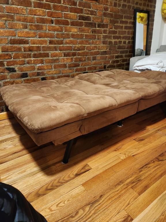 a bed sitting in a room next to a brick wall at In the heart of nyc! Time sq, theater district, javits center in New York