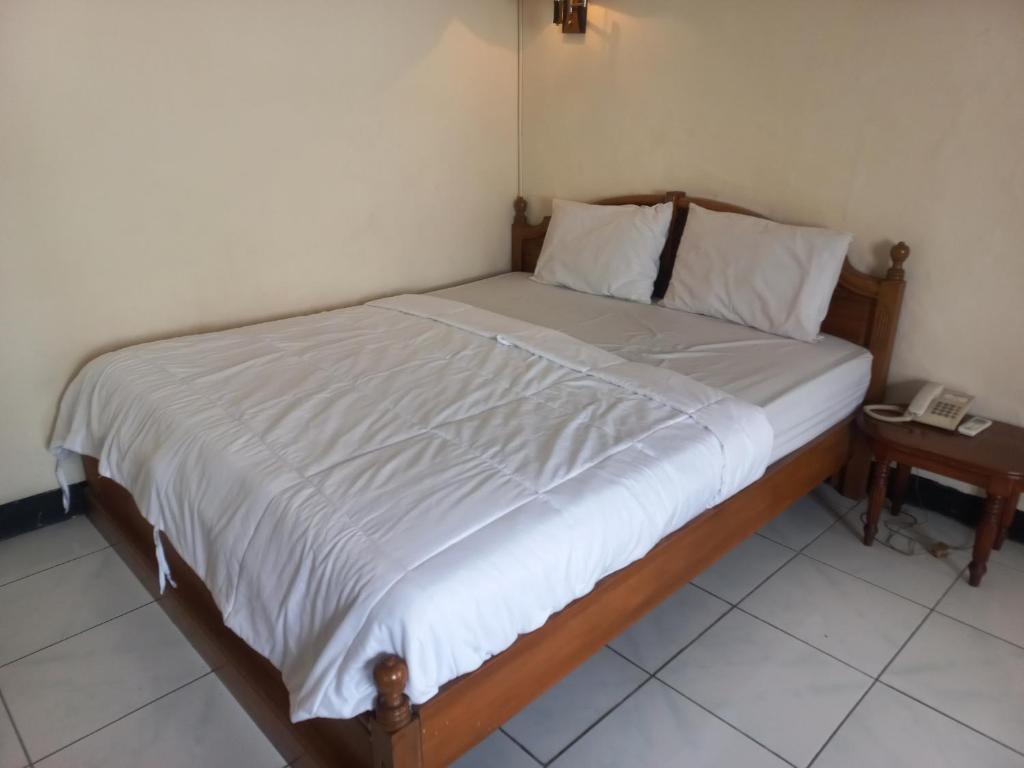 a bed in a bedroom with a phone on a table at Collection O 92242 Hotel Tanjung Emas in Purwokerto