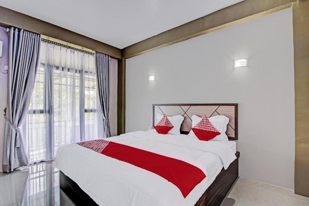 um quarto com uma cama grande e almofadas vermelhas e brancas em OYO 92247 Penginapan Thoybah Syariah 