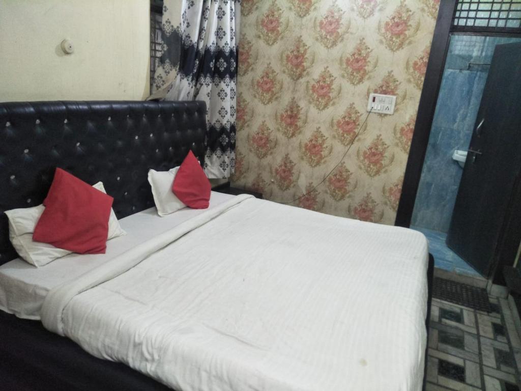 ein Schlafzimmer mit einem Bett mit roten Kissen darauf in der Unterkunft Hotel Shiv Mahima Inn By WB Inn in Allahabad