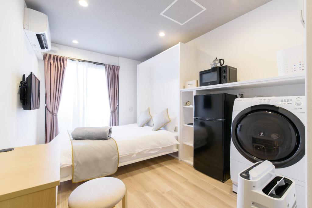 a small room with a bed and a washing machine at JP INN Kyoto Ekimae Izutsucho in Kyoto