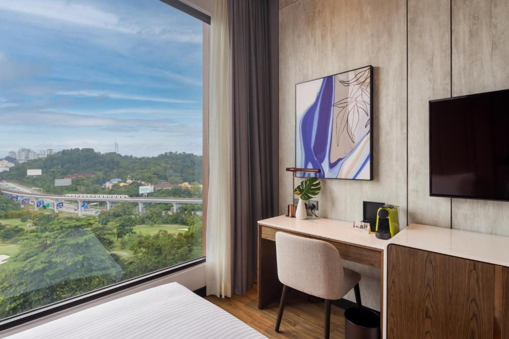 A compact desk beside a large window, with a green hillside and city traffic outside.