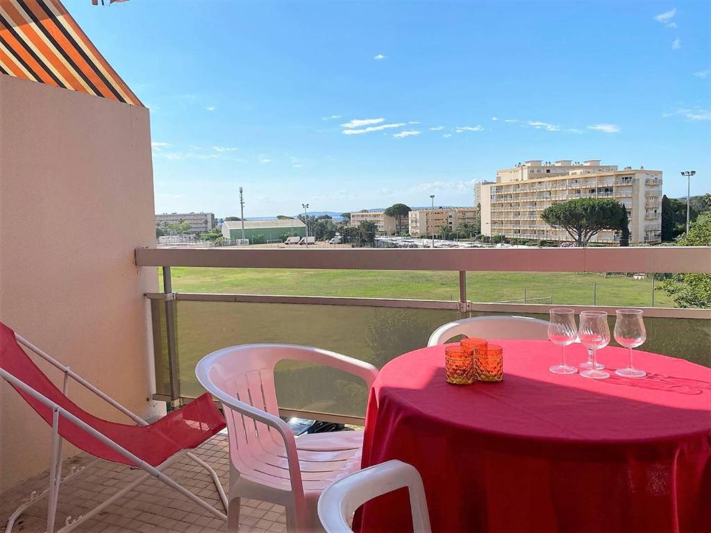 une table rouge avec des chaises et des verres à vin sur un balcon dans l'établissement Studio au Lavandou, Proche Plage, Terrasse, Parking Privatif, 4 Couchages - FR-1-251-236, au Lavandou