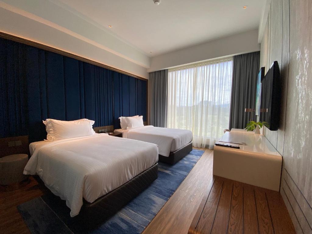 A bright twin room with two beds, a navy feature wall and a television console.