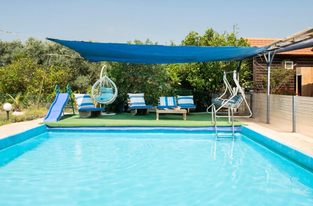 a pool with chairs and a blue canopy over it at Galilaeaen Loft in Chorazim