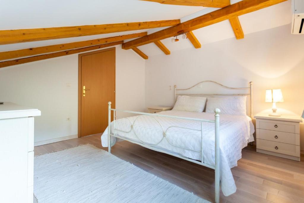 sypialnia z białym łóżkiem i drewnianym sufitem w obiekcie Apartments Svalina w mieście Vantačići