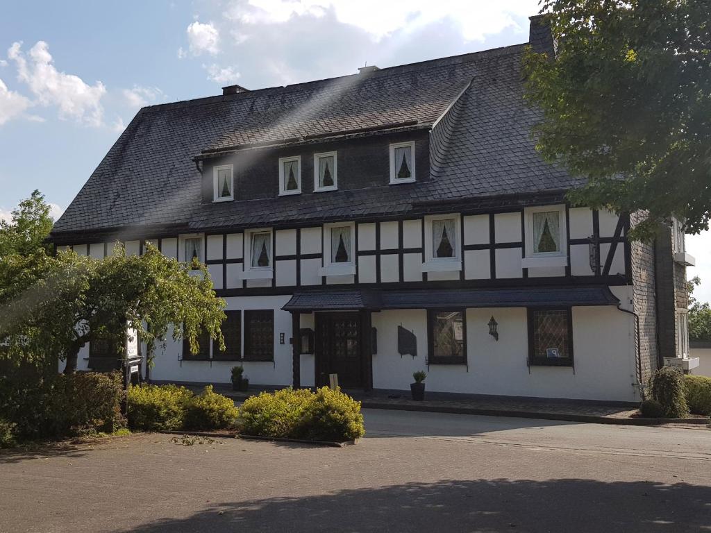 a large white house with a black roof at Landschaftsgasthaus Schanze 1 in Schmallenberg