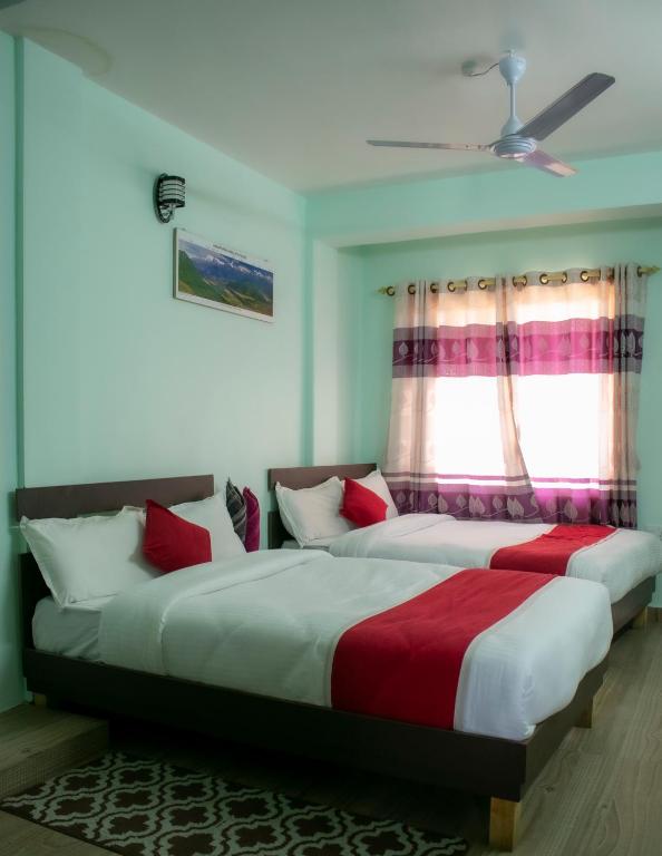 due letti in una camera da letto con finestra di Hotel Elite Pokhara a Pokhara