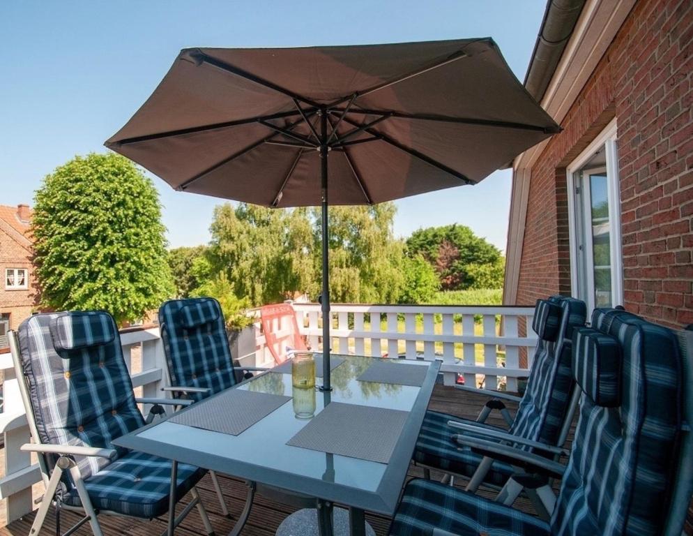 a table with chairs and an umbrella on a balcony at FeWo Hartmann in Strukkamp auf Fehmarn