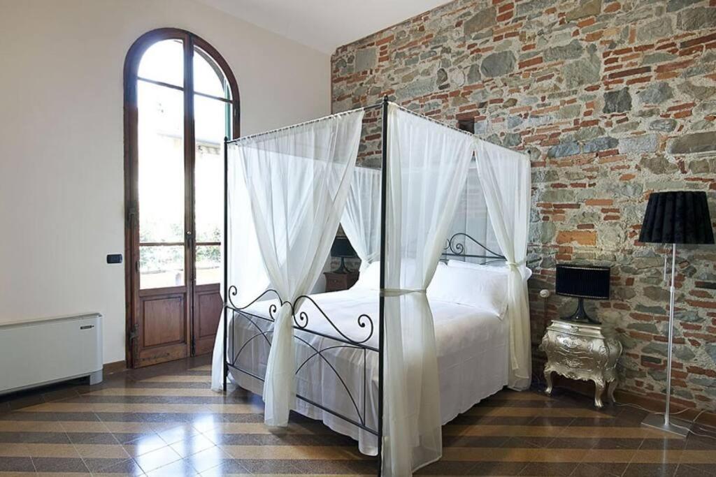 um quarto com uma cama de dossel numa parede de tijolos em Cozy Suite By Villa Il Mosaico em Florença