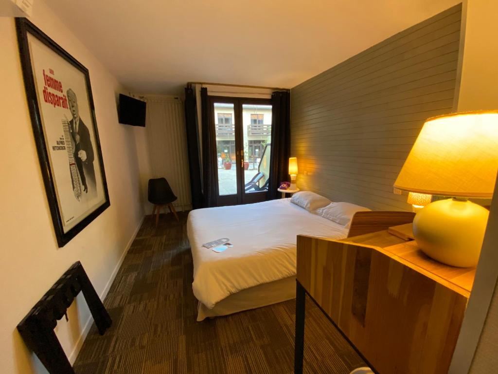 ein Schlafzimmer mit einem Bett und einem Tisch mit einer Lampe in der Unterkunft Enzo Hôtels - ST Eloy Metz Amneville By Kyriad Direct in Amnéville