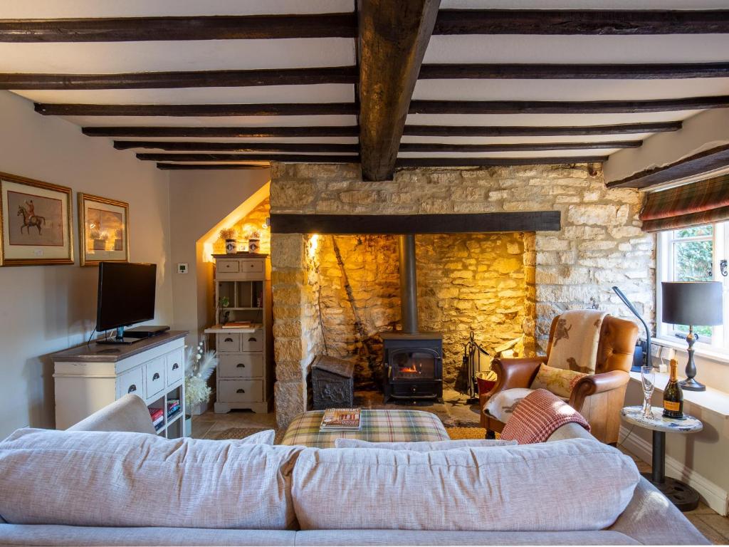 a living room with a couch and a stone fireplace at Thimble Cottage in Lower Slaughter