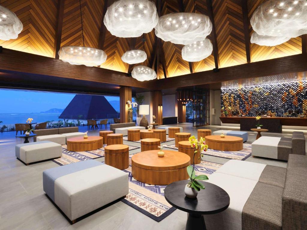 a lobby of a hotel with tables and chairs at Pullman Lombok Merujani Mandalika Beach Resort in Kuta Lombok