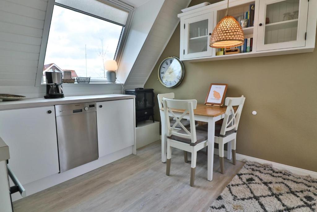 une cuisine avec une table, des chaises et une horloge dans l'établissement Langeooger Viermaster - Gelbes Segel, à Langeoog