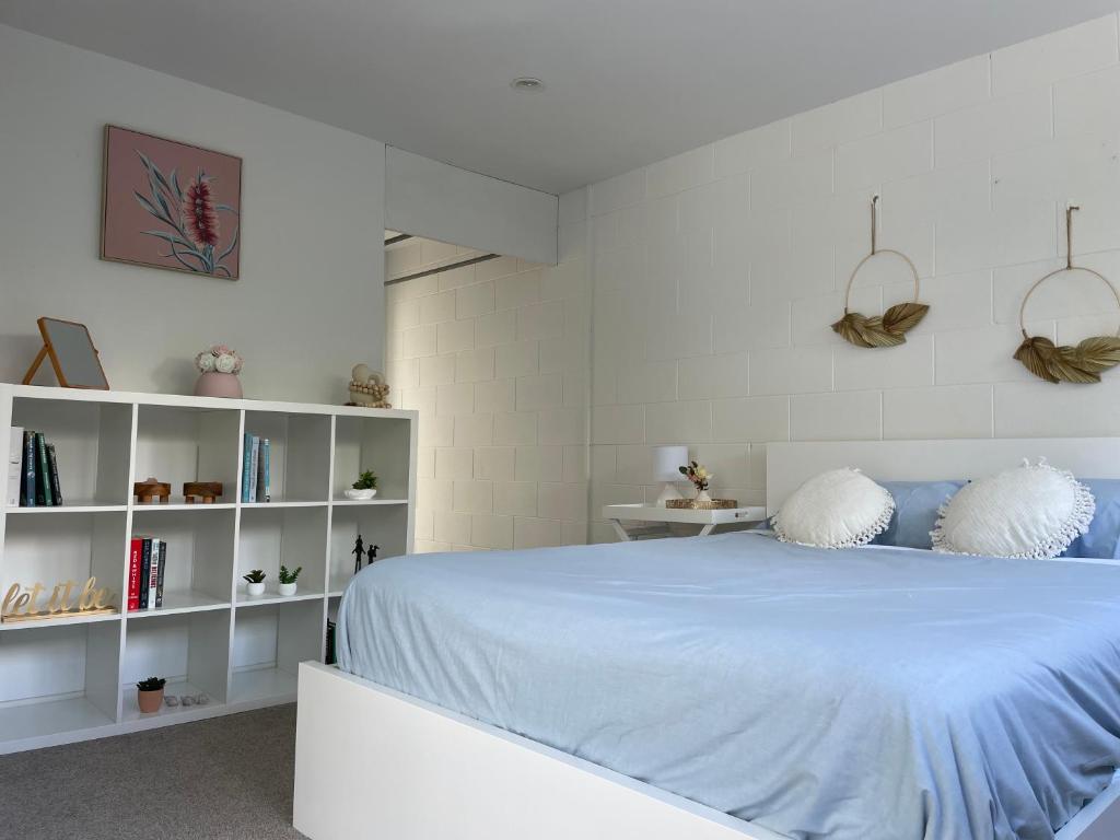 a white bedroom with a bed and white shelves at family friendly 3BR flat - 3min walk to the beach - self contained in Auckland