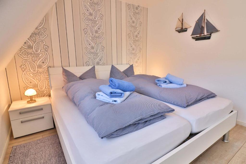 uma cama branca com toalhas azuis em cima em Kiek rin bi Kati - Ferienwohnung 3 em Langeoog