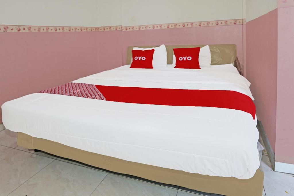uma cama grande com duas almofadas vermelhas em SUPER OYO 92003 Sky Airlines Guesthouse em Tangerang