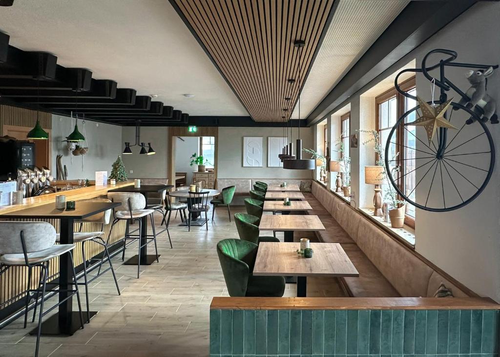un restaurante con mesas de madera y sillas verdes en Hotel Der Drahtesel, en Bramberg am Wildkogel