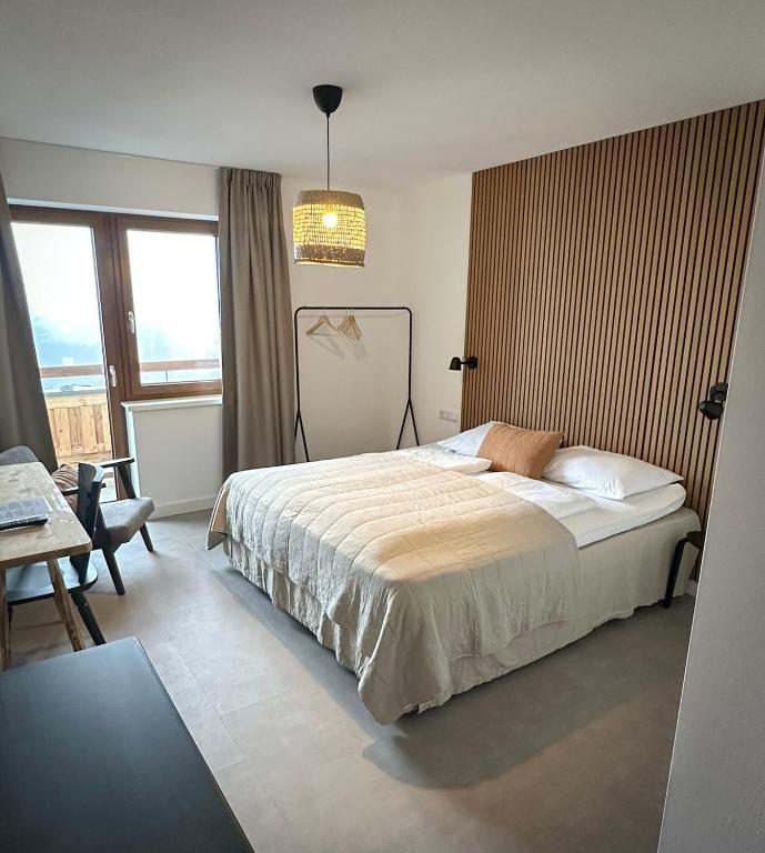 1 dormitorio con cama, mesa y ventana en Hotel Der Drahtesel, en Bramberg am Wildkogel