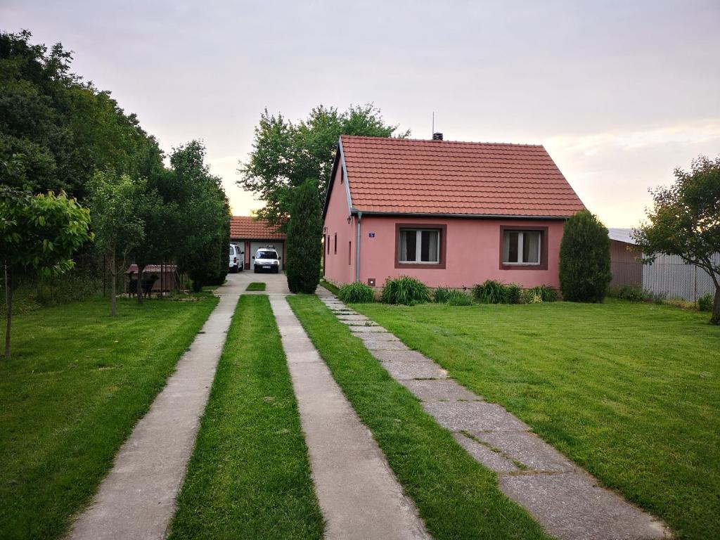 una pequeña casa rosa con un patio de césped en Little village house, en Káty