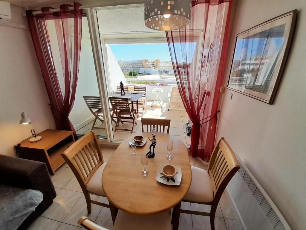 une salle à manger avec une table et des chaises et un balcon dans l'établissement Appartement Village Naturiste Poeme, au Cap d'Agde