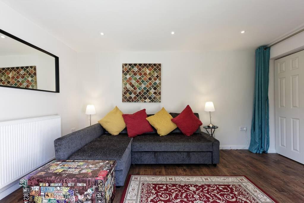 a living room with a gray couch with colorful pillows at Garden Oasis in Margate