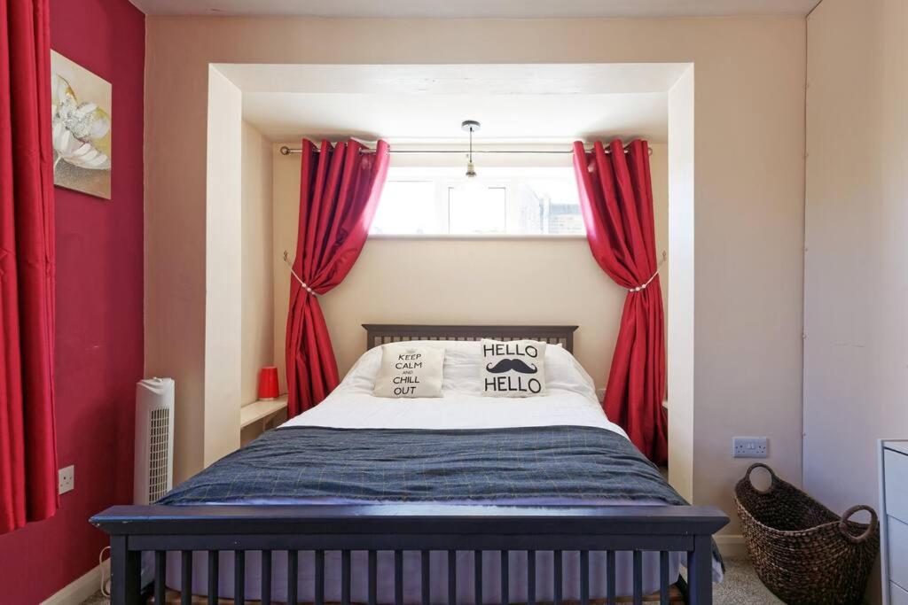 a bedroom with a bed with red curtains and a window at Garden Oasis in Margate