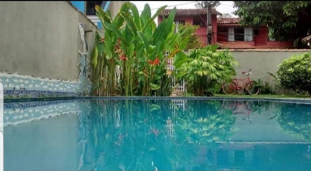 una piscina azul con plantas en un patio en Vila Bahia casa 3, en Porto Seguro