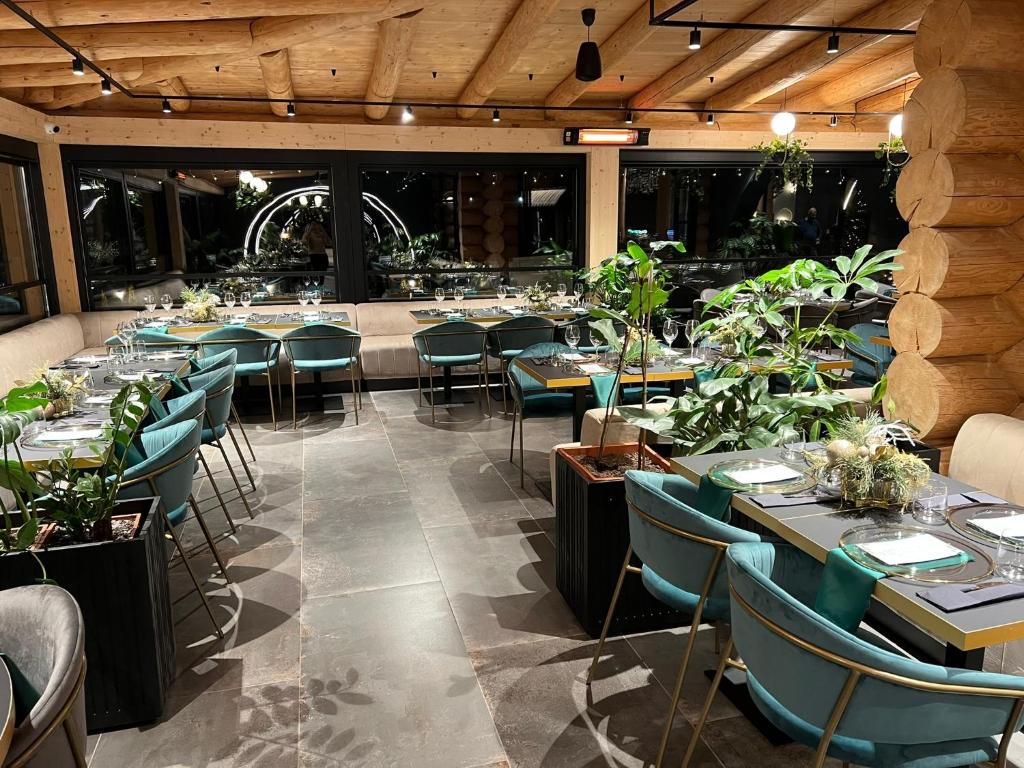 uma sala de jantar com mesas, cadeiras e plantas em Complex Bosco em Borşa
