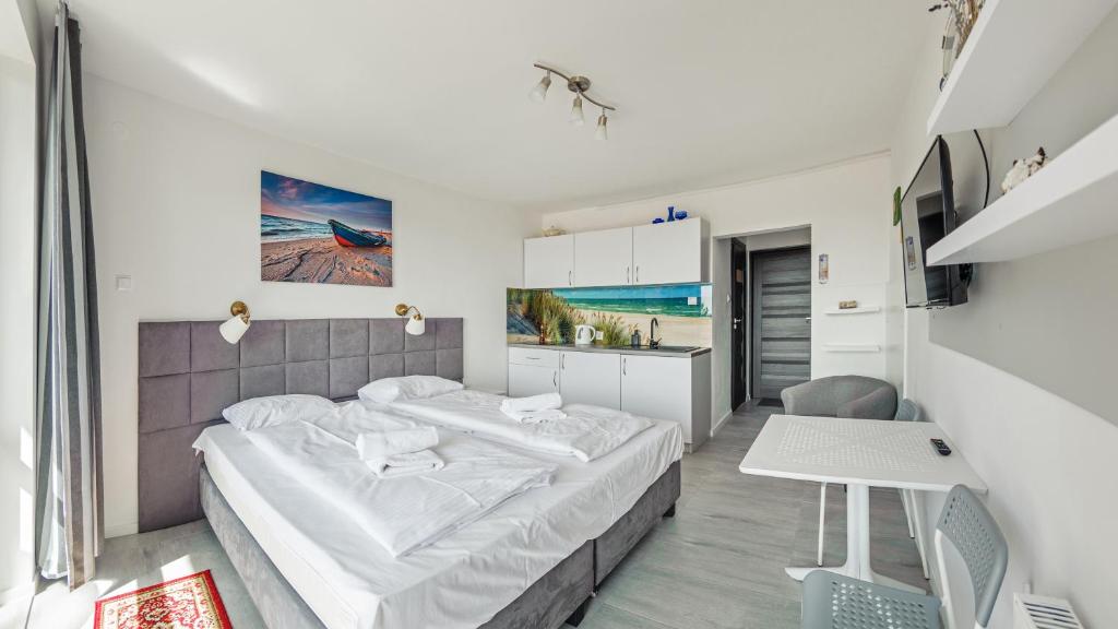 a bedroom with a large bed and a kitchen at Apartamenty Sun & Snow Horyzont in Jastrzębia Góra