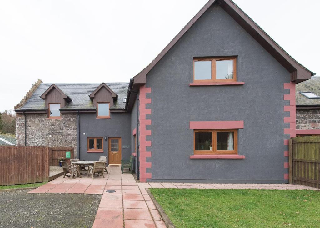 a blue house with a patio and a table at Keepers Lodge with Hot Tub in Forgandenny