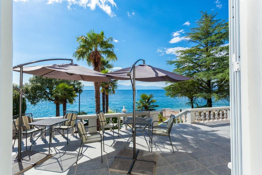 a patio with tables and chairs and the ocean at Rooms Marija in Malinska