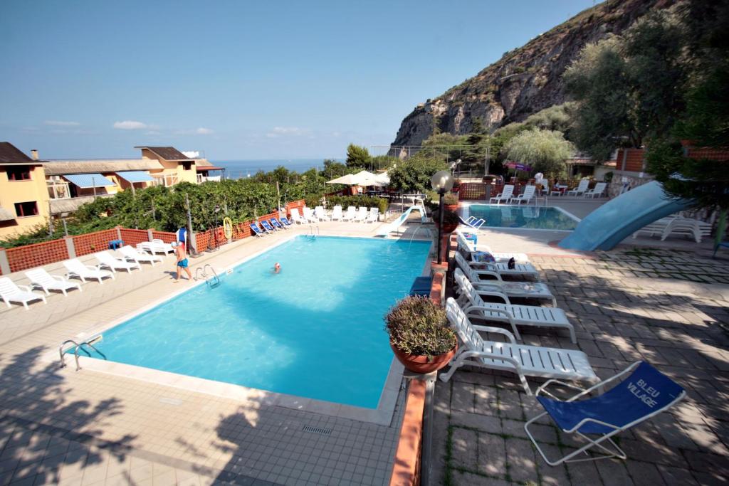 a large swimming pool with chairs and a slide at Bleu Village in Meta