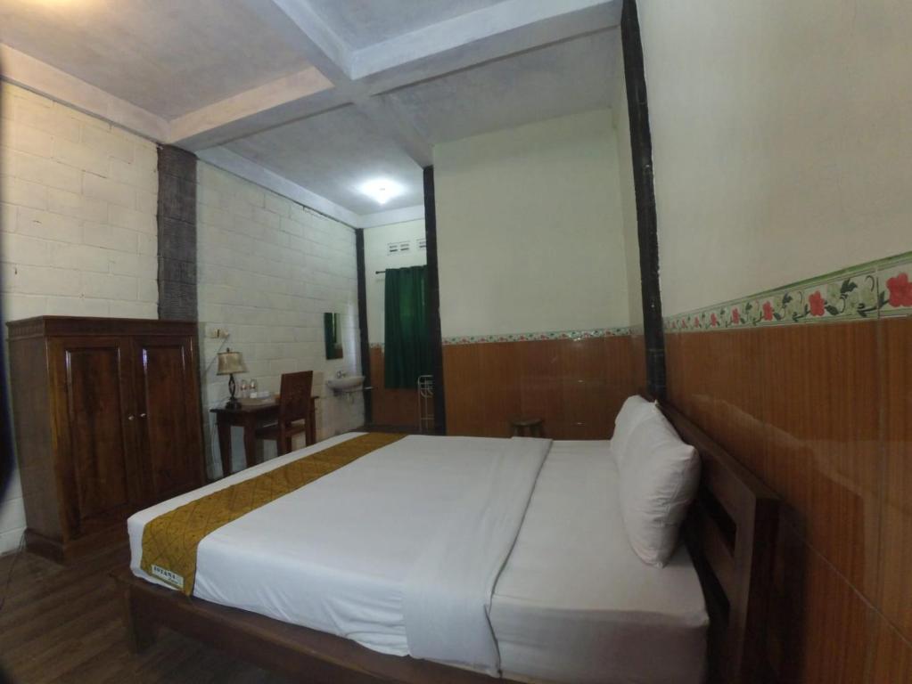 een slaapkamer met een groot wit bed met een houten hoofdeinde bij Istana Petani in Lambangkuning
