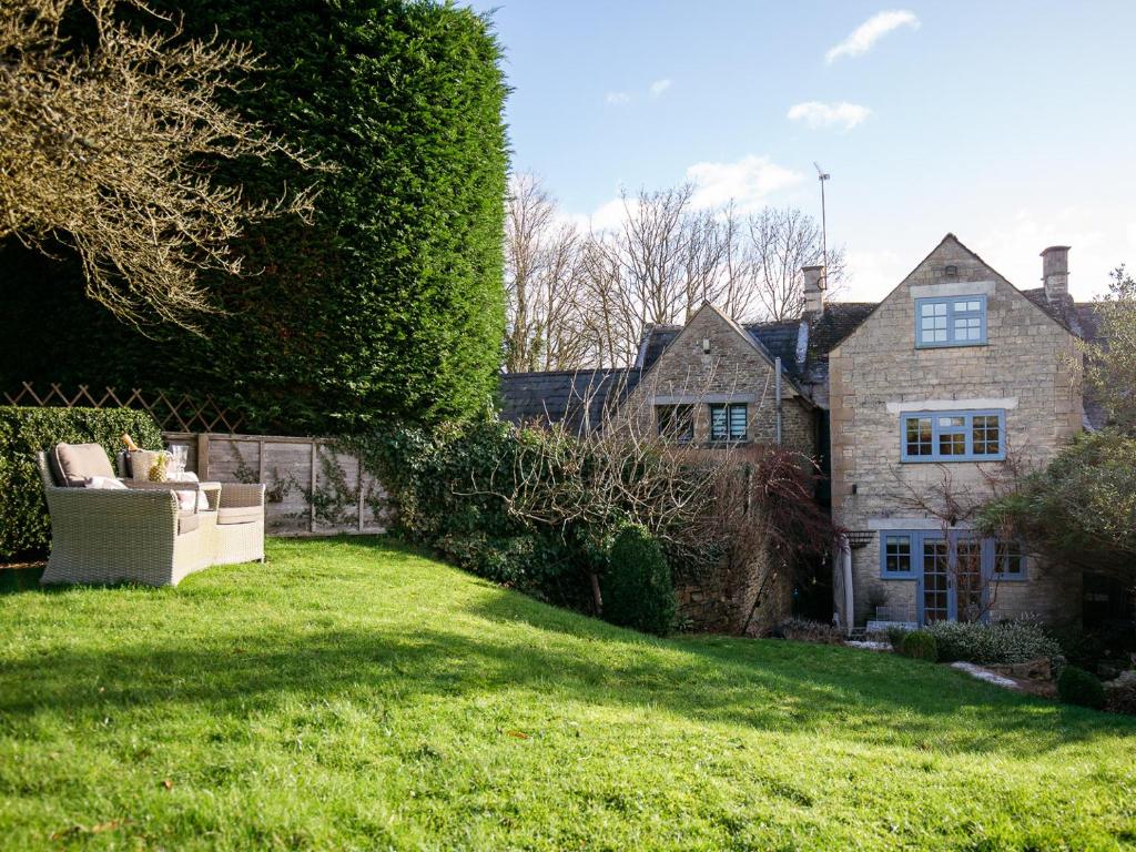 ein Haus mit einem grünen Garten mit einer Couch im Garten in der Unterkunft Pineapple Spa Cottage in Stow on the Wold