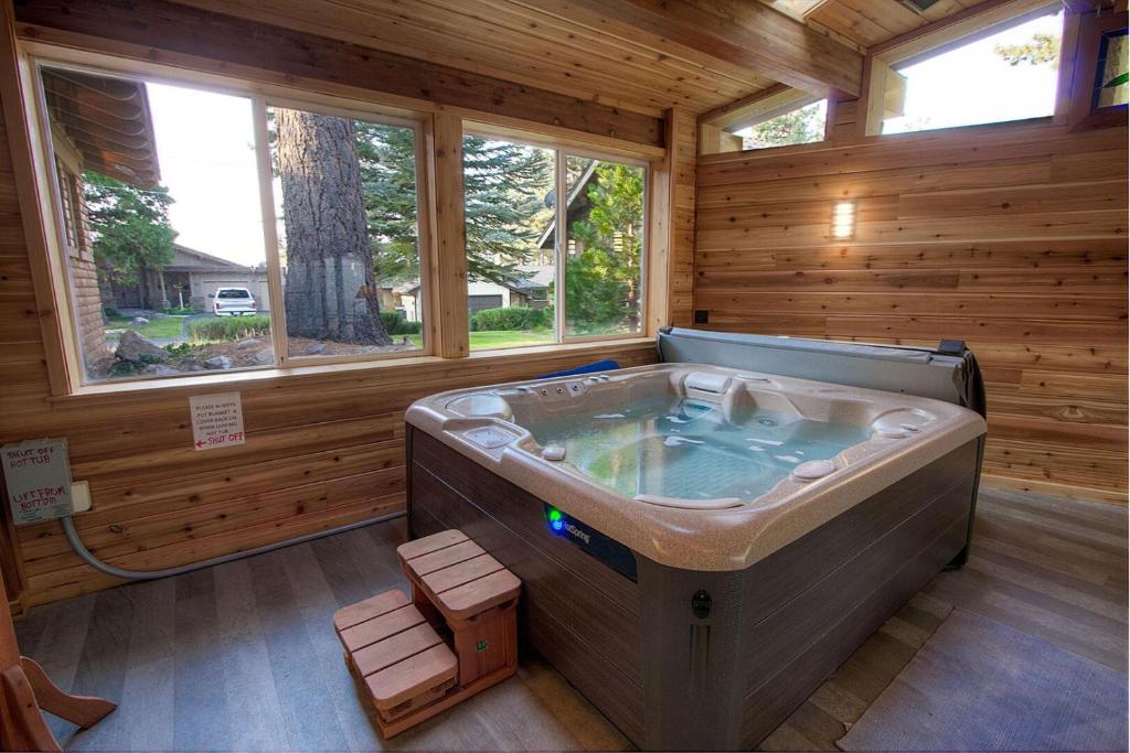 a large tub in a wooden room with windows at Cheyenne Chalet home in Round Hill