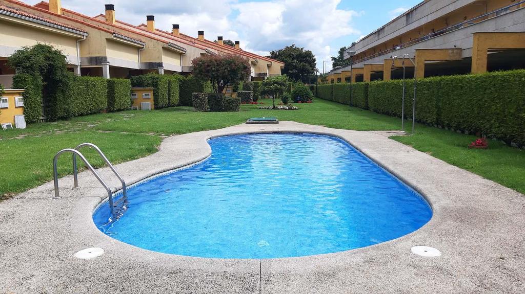 a swimming pool in front of a building at Apartamento con piscina en Portosín in Portosin
