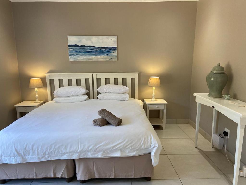 a bedroom with a white bed with two night stands at Loerie Nest in Port Alfred
