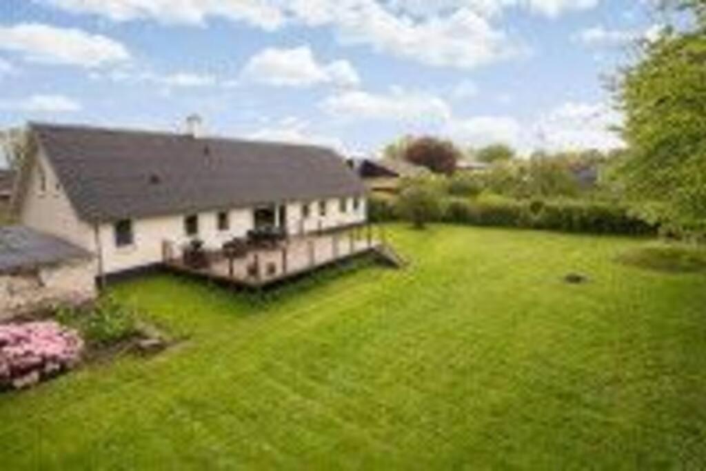 una casa con un gran patio con césped verde en Vidunderligt hus i landlige omgivelser, en Spottrup