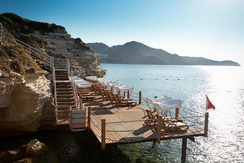 a row of chairs on a dock in the water at Xanadu Island in Akyarlar